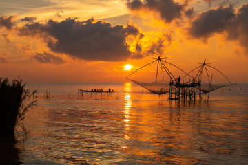 Sunrise sky with fisherman on square dip net and tourism boat at Pakpra village, Phatthalung Province, Thailand