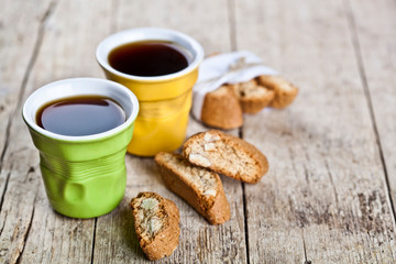 Two cups of coffee, fresh Italian cookies cantuccini and almond seeds on ructic wooden table background.