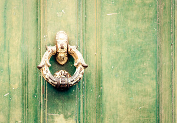 Exterior vintage door knocker metal circle on a wooden door of an ancient building in Catania, Sicily, Italy.
