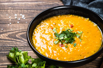 Red lentil soup in black bowl.