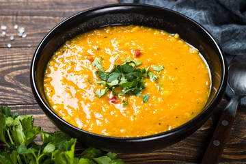 Red lentil soup in black bowl.