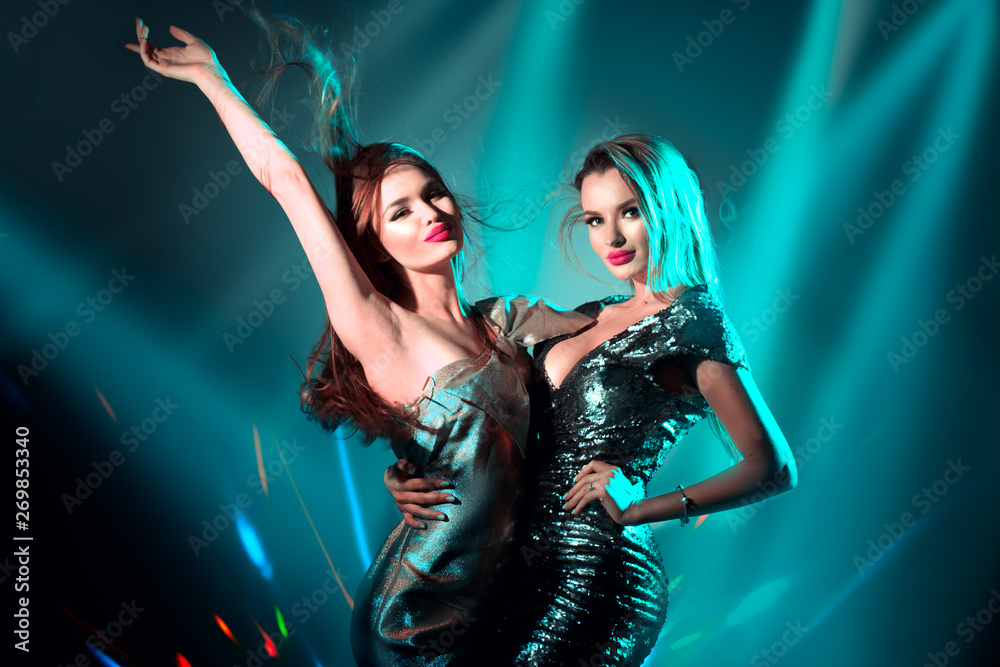 Wall mural Hot model girls dancing in UV neon lights. Disco party. Sexy young women with perfect slim bodies dancing. Night life