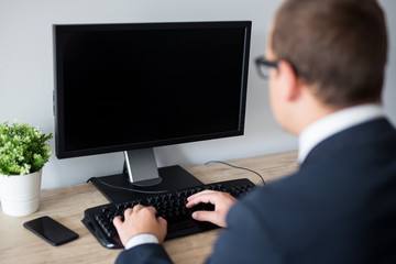 back view of business man using computer in office - blank screen with copy space