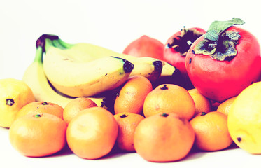 Fruit plate on white background. Mandarins, bananas, persimmons and lemons.