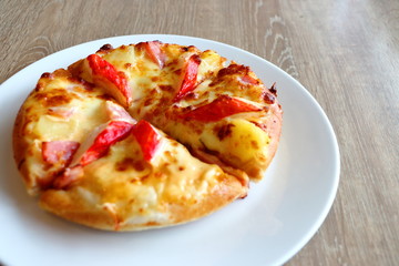 Pizza in a white plate on a wooden table background