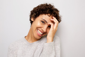 Close up happy young african american woman laughing with hand by head by white wall