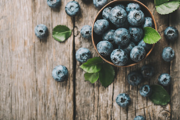 Freshly picked blueberries in wooden bowl on wooden background. Healthy eating and nutrition.