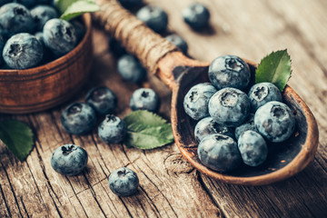 Blueberries in wooden spoon on old wood table. Healthy eating and nutrition concept.