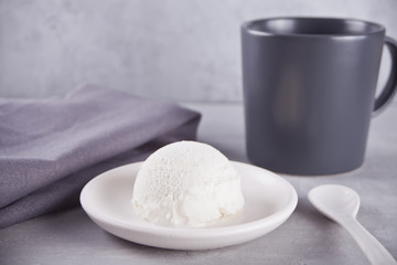 Ice cream on a white ceramic plate with gray napkin and gray mug on a gray table