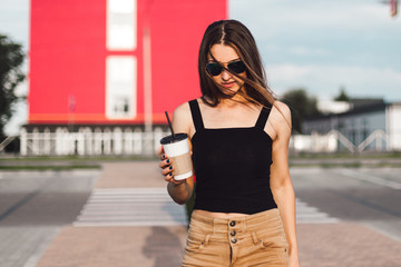 Fototapeta premium Happy young woman drink coffee walking on the street.