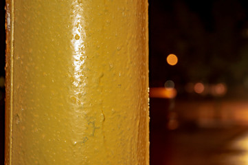 Yellow lamp post with drops of water at night Close up