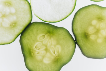green translucent slices of cucumber on the background of bright white light close-up. transparent discs of vegetables. texture of kaleidoscope patterns in macro