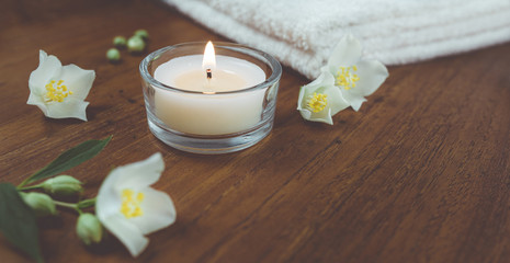 Obraz na płótnie Canvas Spa und Wellness Kerze, Jasmin Blüten, Handtücher auf Holz