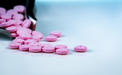 Pink tablets pills on blurred background of drug tray. Pharmaceutical industry. Pharmacy products. Vitamins and supplements. Medication use in hospital or drugstore. Global drug retail market.