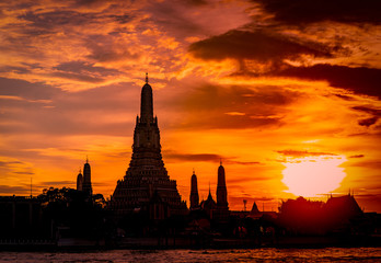 Obraz premium Wat Arun Ratchawararam at sunset with beautiful red and orange sky and clouds. Wat Arun buddhist temple is the landmark in Bangkok, Thailand. Attraction art. Silhouette dramatic sky and temple.