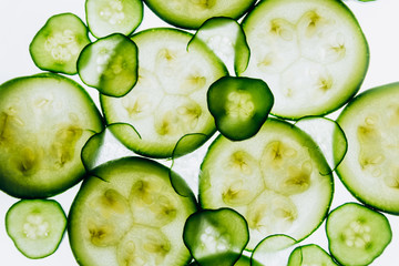 green translucent slices of cucumber on the background of bright white light close-up. transparent discs of vegetables. texture of kaleidoscope patterns in macro