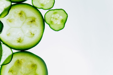 green translucent slices of cucumber on the background of bright white light close-up. transparent discs of vegetables. texture of kaleidoscope patterns in macro