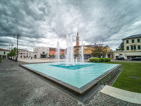 Azzano Decimo di Pordenone, piazza cittadina con la fontana in una giornata di temporale