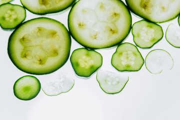 green translucent slices of cucumber on the background of bright white light close-up. transparent discs of vegetables. texture of kaleidoscope patterns in macro