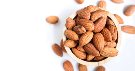 Almond nuts in wooden bowl on white background.