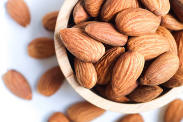 Almond nuts in wooden bowl on white background.
