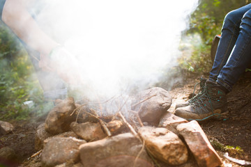 A girl sits by the fire in the woods drinking tea and roasting marshmallows