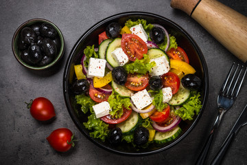 Greek salad in black plate on the table.