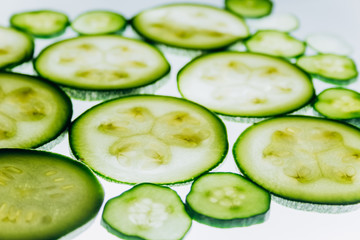 green translucent slices of cucumber on the background of bright white light close-up. transparent discs of vegetables. texture of kaleidoscope patterns in macro
