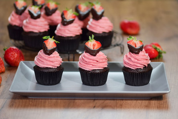 Fresh homemade chocolate cupcakes with buttercream and strawberries.