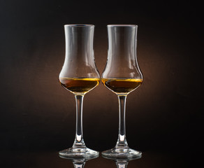 Two glasses of cognac sniffer on a colored dark background