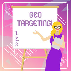 Text sign showing Geo Targeting. Business photo showcasing method of determining the geolocation of a website visitor White Female in Glasses Standing by Blank Whiteboard on Stand Presentation