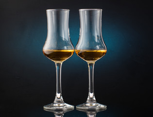 Two glasses of cognac sniffer on a colored dark background