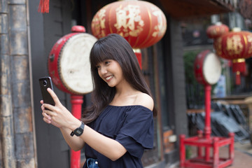 Fototapeta na wymiar young asian woman enjoy with smart phone in China town