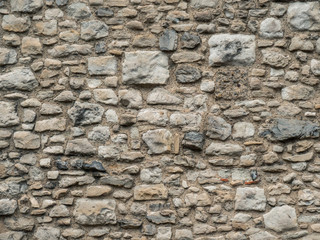 Old beige stone wall background texture close up. Texture of a stone wall. Old castle stone wall texture background. Stone wall as a background or texture. Part of a stone wall, for background.