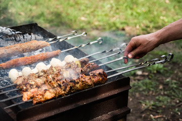  man's hand turns the barbecue on the grill