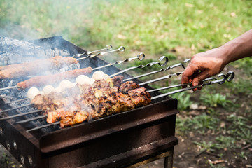  man's hand turns the barbecue on the grill