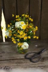 a bouquet of buttercups and wild white roses on the old bench in gazebo