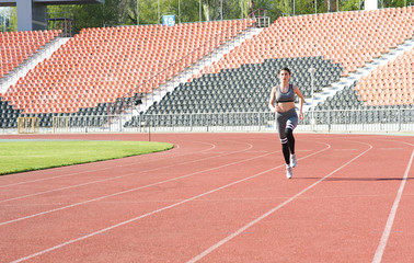Fototapeta premium Beautiful athletic girl running around the stadium