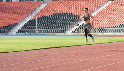 Beautiful athletic girl running around the stadium