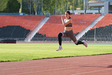 Beautiful athletic girl running around the stadium