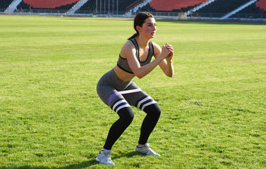 Beautiful athletic girl crouches on the grass in the stadium