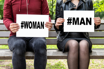 Hashtags with words - woman, man. Couple sitting on a bench at the park, , gender concept
