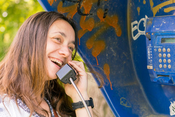 Beautiful young girl in a phone booth. The girl is talking on the phone from the payphone. pretty...