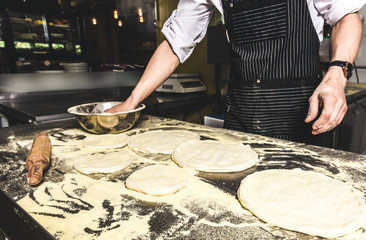 Professional chef cooking in the kitchen restaurant at the hotel, preparing dinner. A cook in an apron makes a salad of vegetables and pizza.