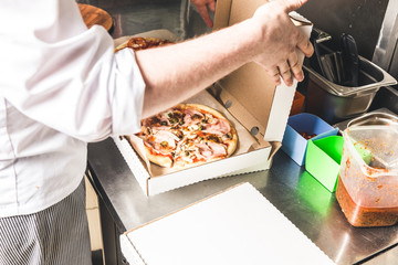 Professional chef cooking in the kitchen restaurant at the hotel, preparing dinner. A cook in an apron makes a salad of vegetables and pizza.