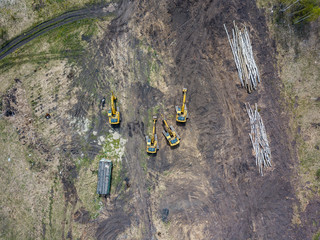 Aerial view of the four yellow crawler excavators that stand on the ground near the construction...
