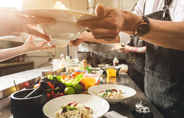 Professional chef cooking in the kitchen restaurant at the hotel, preparing dinner. A cook in an apron makes a salad of vegetables and pizza.