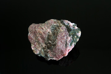 Macro stone Rhodonite mineral on a black background. Origin: Russia, Ural.