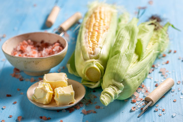 Before grilling corncob with butter and salt on blue table