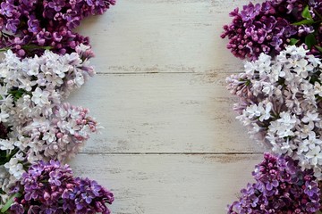 Frame with colored lilac on white wooden background close-up